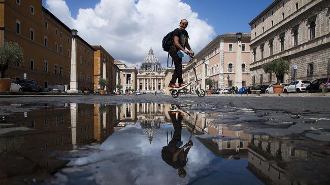 A man rides a scooter on June 8, 2020 on Via della Conciliazione in Rome near The Vatican and its Basilica (Rear) as the country eases its lockdown aimed at curbing the spread of the COVID-19 infection, caused by the novel coronavirus. (Photo by Tiziana FABI / AFP)