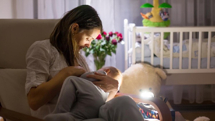 menyusui malam hari Young beautiful mother, breastfeeding her newborn baby boy at night, dim light. Mom breastfeeding infant