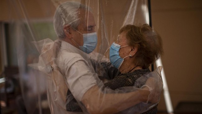 In their first encounter in more than 100 days due to restrictions to fight the coronavirus pandemic, Isabel Pérez López, 96, receives an embrace through a plastic film screen from her visiting son-in-law Jose Maria Vila, 69, at a nursing home in Barcelona, Spain, Monday, June 22, 2020. The Ballesol Fabra i Puig elderly care center installed the screens to resume relatives' visits to residents. In the presence of tearful nursing home workers, mother and daughter held each other for minutes through the layers of plastic. Segura said she was looking forward to take her mother out for a meal at a restaurant while López said she looked forward to visiting a beauty salon for a long-overdue haircut. Nursing homes in Spain have been particularly hit by the novel virus, which has claimed at least 28,300 lives nationwide. (AP Photo/Emilio Morenatti)