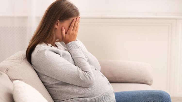 ibu hamil menangis Depression And Pregnancy. Pregnant Lady Crying Covering Face With Hands Sitting On Sofa At Home.