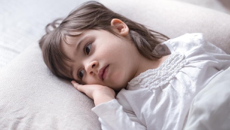 1142675894 Cute little girl is sad lying in a white cozy bed , the concept of children's rest and sleep