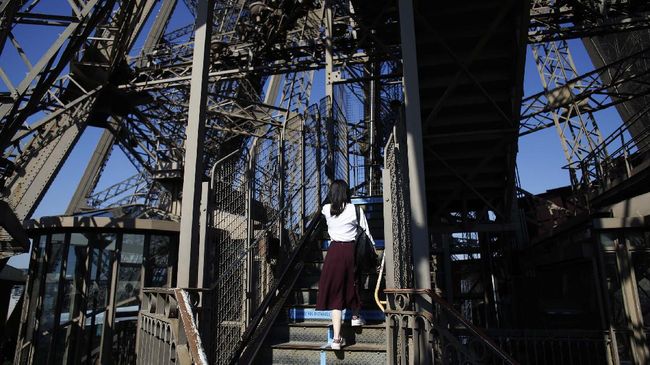 A visitor climbs the stairs of the Eiffel Tower, in Paris, Thursday, June 25, 2020. The Eiffel Tower reopens after the coronavirus pandemic led to the iconic Paris landmark's longest closure since World War II. (AP Photo/Thibault Camus)