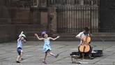 Nyalang Edisi 27 Juni 2020 Two children dance as they listen to a street musician on May 22, 2020 in Strasbourg, eastern France, after the city of Strasbourg on May 20, issued a decree making the wearing of masks