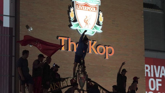 Liverpool supporters celebrate as they gather outside of Anfield Stadium in Liverpool, England, Friday, June 26, 2020 after Liverpool clinched the English Premier League title. Liverpool took the title after Manchester City failed to beat Chelsea on Wednesday evening. (AP photo/Jon Super)