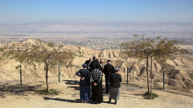 File - In this Sunday, Jan. 26, 2020 file photo, Jewish settlers stand at a view point overlooking the West Bank city of Jericho from the Jewish settlement of Mitzpe Yeriho. Israeli Prime Minister Benjamin Netanyahu has vowed to annex the valley and all of Israel's far-flung West Bank settlements, in line with President Donald Trump's Middle East plan, which overwhelmingly favors Israel and has been rejected by the Palestinians. (AP Photo/Oded Balilty, File)
