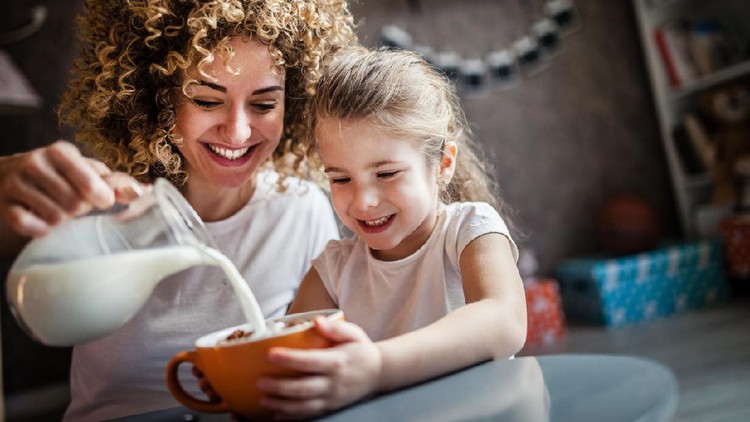 1137245560 Portrait of adorable young girl and mother having breakfast
