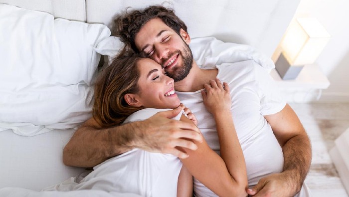 Beautiful loving couple kissing in bed. beautiful young couple lying together on the bed. Romantic young couple in love lying on bed. Beautiful couple smiling in bed.
