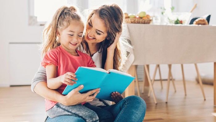 Mother and daughter reading book on the floor.