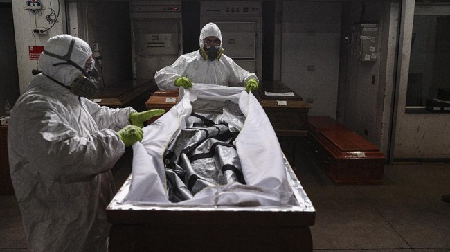 Employees prepare to cremate the body of a person who died from the new coronavirus, at La Recoleta crematorium in Santiago, Chile, Saturday, June 27, 2020. The Ministry of Health reported on Saturday the highest number of deaths in Chile since the start of the pandemic. (AP Photo/Esteban Felix)