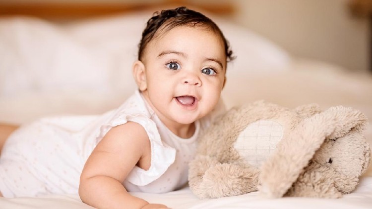 1160269739 Shot of a cute baby girl on bed with a soft toy