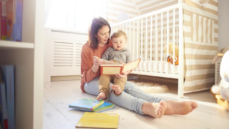 young mother reading a story to her toddler in his bedroom