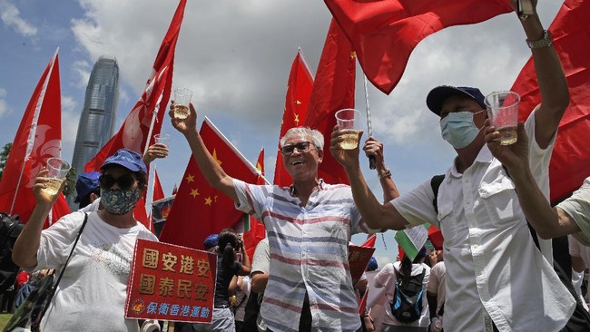 Pro-China supporters holding Chinese national flags, toast during a rally to celebrate the approval of a national security law for Hong Kong, in Hong Kong, Tuesday, June 30, 2020. Hong Kong media are reporting that China has approved a contentious law that would allow authorities to crack down on subversive and secessionist activity in Hong Kong, sparking fears that it would be used to curb opposition voices in the semi-autonomous territory. A placard reads 