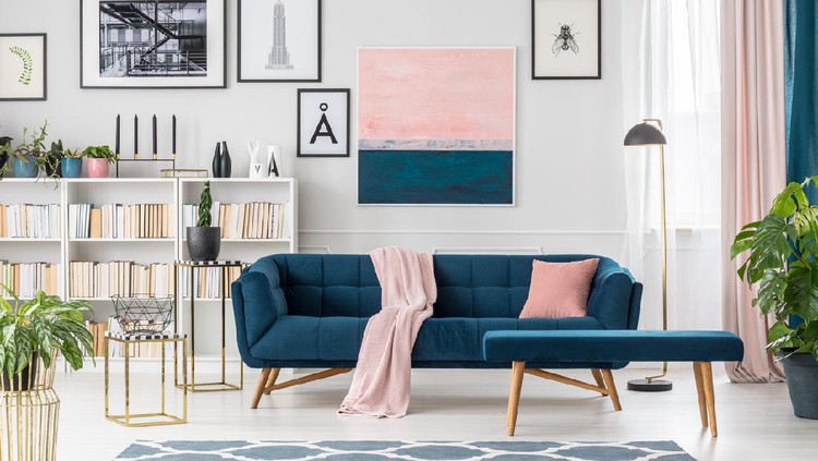 Blue bench and settee with pink blanket in elegant living room interior with bookshelf and posters