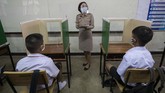 Anak-anak Thailand Kembali Masuk Sekolah A teacher in protective gear teaches her students, seated at partitioned desks at the Samkhok School in Pathum Thani, outside Bangkok, Wednesday, July 1, 2020. Thailand has begun a fifth phase of relaxations of COVID-19 restrictions, allowing the reopening of schools and high-risk entertainment venues such as pubs and massage parlors that had been shut since mid-March. (AP Photo/Sakchai Lalit)