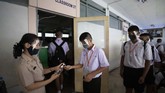 Anak-anak Thailand Kembali Masuk Sekolah Teacher in protective gear offers hand sanitizer to students before class at the Samkhok School in Pathum Thani, outside Bangkok, Wednesday, July 1, 2020. Thailand has begun a fifth phase of relaxations of COVID-19 restrictions, allowing the reopening of schools and high-risk entertainment venues such as pubs and massage parlors that had been shut since mid-March. (AP Photo/Sakchai Lalit)