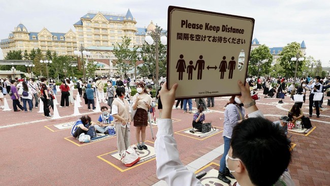People wearing face masks to protect against the spread of the new coronavirus demonstrate the social distancing before they wait to enter Tokyo Disneyland in Urayasu, near Tokyo, Wednesday, July 1, 2020. Tokyo Disneyland reopens for the first time in four months after suspending operations due to coronavirus concerns. (Kyodo News via AP)