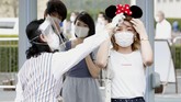 Disneyland Jepang dibuka A visitor has her body temperature checked at the entrance of Tokyo Disneyland in Urayasu, near Tokyo, Wednesday, July 1, 2020. Tokyo Disneyland reopened for the first time in four months after suspending operations due to coronavirus concerns. (Kyodo News via AP)