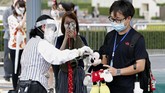 disneyland Jepang dibuka A visitor gestures to have the body temperature of a Mickey Mouse doll checked at the entrance of Tokyo Disneyland in Urayasu, near Tokyo, Wednesday, July 1, 2020. Tokyo Disneyland reopened for the first time in four months after suspending operations due to coronavirus concerns. (Kyodo News via AP)