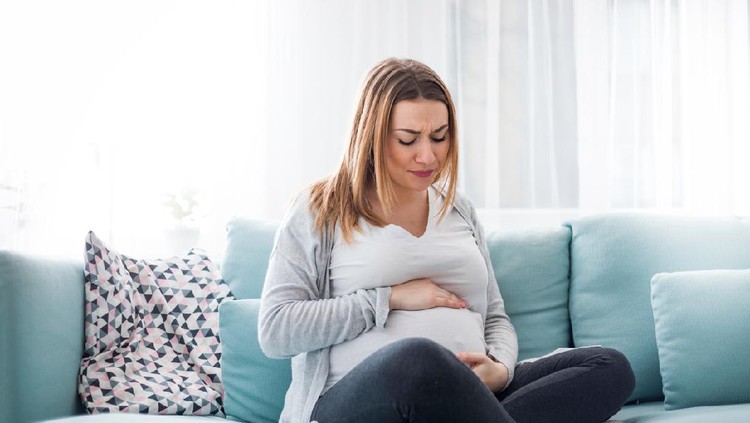 Young pregnant woman suffering from abdominal pain at home