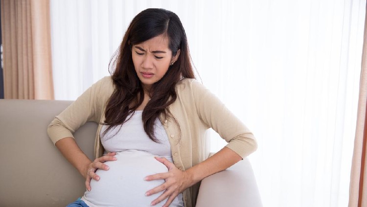 Young pregnant woman suffering from abdominal pain at home