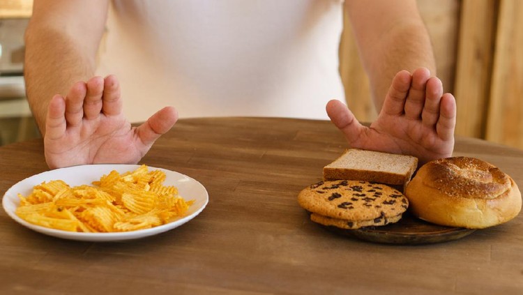 Intermittent fasting concept with clock on white plate, fork and knife on blue table