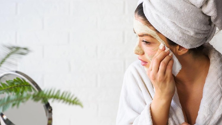 Young woman applying face mask at home. Natural Skin Care Routine For Glowing Skin.