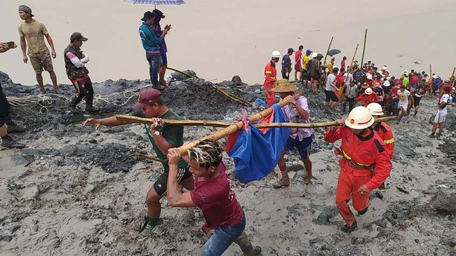 In this photo released from Myanmar Fire Service Department, rescuers carry a recovered body of a victim in a landslide from a jade mining area in Hpakant, Kachin state, northern Myanmar Thursday, July 2, 2020. Myanmar government says a landslide at a jade mine has killed dozens of people. (Myanmar Fire Service Department via AP)