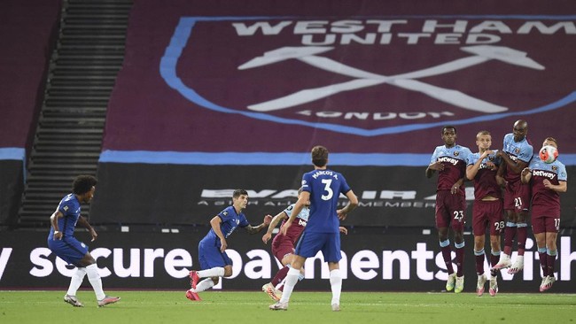 Chelsea's Willian, left curls the ball past the wall to score his second goal during the English Premier League soccer match between West Ham United and Chelsea at the London Stadium stadium in London, Wednesday July 1, 2020. (Michael Regan/Pool via AP)