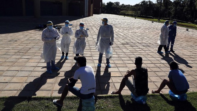 Members of the National Mechanism to Prevent Torture (MNPT) interview youths at a sports facility that was turned into a government-run shelter where citizens returning home are required by law to quarantine for two weeks and pass two consecutive COVID-19 tests, as a preventive measure amid the COVID-19 pandemic in Hermandarias, Paraguay, near the border with Brazil, Thursday, June 24, 2020. With only 7 million people, a stagnant economy, high poverty, and a weak public health system, Paraguay moved to slow coronavirus in March by closing borders and imposing the quarantine restrictions, along with closing schools and public events and declaring a nighttime curfew.  (AP Photo/Jorge Saenz)