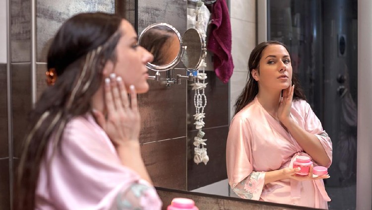 Ibu hamil Young pregnant woman with cosmetic cream in a bathroom. Concept body care.