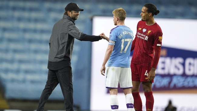 Liverpool's manager Jurgen Klopp, left, gestures with Manchester City's Kevin De Bruyne after as Liverpool's Virgil van Dijk watches the English Premier League soccer match between Manchester City and Liverpool at Etihad Stadium in Manchester, England, Thursday, July 2, 2020. (AP Photo/Dave Thompson,Pool)