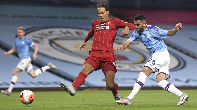 Manchester City's Riyad Mahrez, right, attempts a shot on goal during the English Premier League soccer match between Manchester City and Liverpool at Etihad Stadium in Manchester, England, Thursday, July 2, 2020. (AP Photo/Laurence Griffiths,Pool)