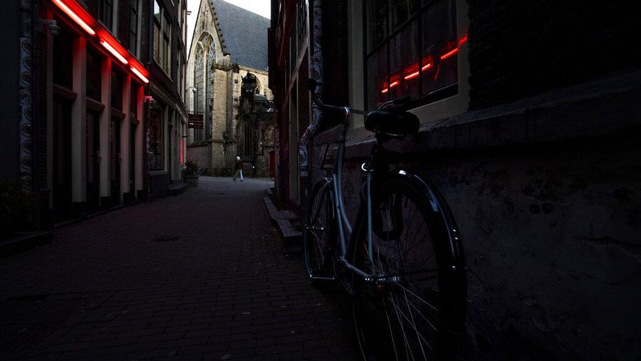 Virus Outbreak Netherlands Red Light District Oude Kerk, or Old Church, is reflected in the window of the PIC, Prostitution Information Center, as sex workers welcomed clients again in the Red Light District in Amsterdam, Netherlands, Wednesday, July 1, 2020. It wasn't quite business as usual as the capital's Red Light District emerged from coronavirus lockdown, but it was as close as it has been since the pandemic slammed the brakes on the world's oldest profession. (AP Photo/Peter Dejong)