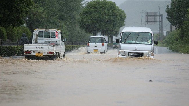 Vehicles pass through a flooded road caused by heavy rain in Yatsushiro, Kumamoto prefecture on July 4, 2020. - Some 75,000 people were ordered to evacuate in western Japan on July 4 as record heavy rain triggered floods and landslides, local media and officials said. The nation's weather agency issued the highest level of heavy rain warnings to Kumamoto and Kagoshima on Kyushu island. (Photo by STR / JIJI PRESS / AFP) / Japan OUT