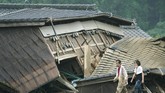 Banjir Bandang Jepang Tewaskan 20 Orang A couple walks in front of houses damaged by flood in Kuma village, Kumamoto prefecture, southwestern Japan, Sunday, July 5, 2020. Heavy rain in the Kumamoto region triggered flooding and mudslides Saturday and left dozens still being stranded at their homes and other facilities. (Koji Harada/Kyodo News via AP)