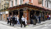 Pub di Inggris Kembali Dibuka People stand outside a pub in Soho, as the capital is set to reopen after the lockdown due to the Coronavirus outbreak, in London, Saturday, July 4, 2020. England is embarking on perhaps its biggest lockdown easing yet as pubs and restaurants have the right to reopen for the first time in more than three months. In addition to the reopening of much of the hospitality sector, couples can tie the knot once again, while many of those who have had enough of their lockdown hair can finally get a trim. (AP Photo/Alberto Pezzali)