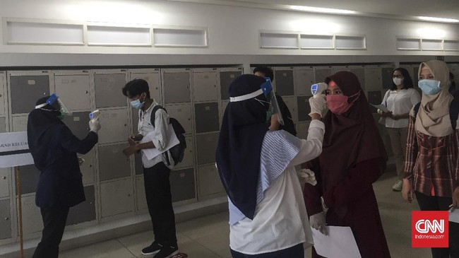 Peserta Seleksi Bersama Masuk Perguruan Tinggi Negeri berbaris dan melakukan pemeriksaan suhu sebelum memasuki ruang Ujian Tes Berbasis Komputer di Universitas Indonesia, Senin (6/7).