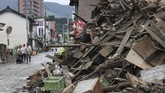 Pencarian Korban Banjir di Jepang People walk near piled-up debris from a heavy rain in Hitoyoshi, Kumamoto prefecture, southern Japan Monday, July 6, 2020. Rescue operations continued and rain threatened wider areas of the main island of Kyushu. (Kyodo News via AP)