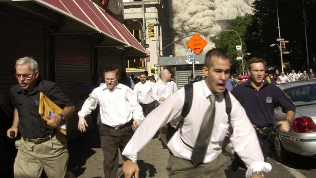 FILE - In this Sept. 11, 2001, file photo, people run from the collapse of one of the twin towers at the World Trade Center in New York. Stephen Cooper, far left, fleeing smoke and debris as the south tower crumbled just a block away on Sept. 11, has died from coronavirus, his family said, according to The Palm Beach Post. (AP Photo/Suzanne Plunkett, File)