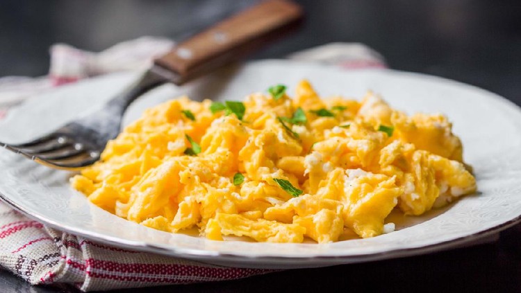 Ilustrasi scrambeled egg Preparing scrambled eggs in a pan, close-up.