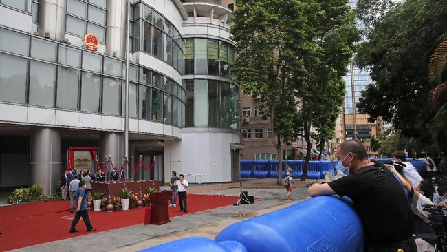 A man looks over the water-filled barriers after an opening ceremony for the China's new Office for Safeguarding National Security in Hong Kong, Wednesday, July 8, 2020. China's new national security office in Hong Kong got off to an early start on Wednesday with an official opening amidst heavy police presence. (AP Photo/Kin Cheung)