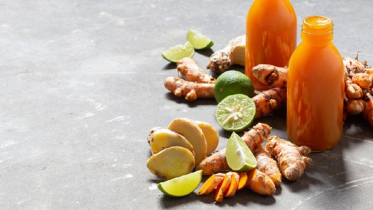 Healthy drink from turmeric and ginger roots and lime in small bottles on grey concrete background with copyspace. Jamu - popular Indonesian traditional drink on Bali. Immunity boosting, detox, diet.