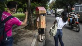 Seorang Nenek di Kuba Tangkal Corona Dengan Kardus Passersby take photos of Feridia Rojas, a retired nurse, wearing her cardboard box as a protective measure against the spread of the new coronavirus, in Havana, Cuba, Wednesday, July 8, 2020. The 82-year-old pensioner shuffles through the streets of Havana on shopping excursions wearing the cardboard box, with a handwritten message that reads in Spanish,