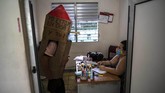 Seorang Nenek di Kuba Tangkal Corona Dengan Kardus Retired nurse Feridia Rojas wearing a cardboard box as a protective measure against the spread of the new coronavirus, stops in for a friendly visit with the family doctor, in Havana, Cuba, Wednesday, July 8, 2020. The 82-year-old pensioner shuffles through the streets of Havana on shopping excursions wearing the cardboard box, with a handwritten message that reads in Spanish,