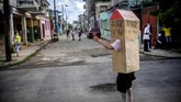 Seorang Nenek di Kuba Tangkal Corona Dengan Kardus Retired nurse Feridia Rojas wears a cardboard box as a protective measure against the spread of the new coronavirus, in Havana, Cuba, Wednesday, July 8, 2020. The 82-year-old pensioner shuffles through the streets of Havana on shopping excursions wearing the cardboard box, with a handwritten message that reads in Spanish,