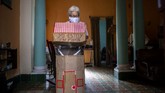 Seorang Nenek di Kuba Tangkal Corona Dengan Kardus Retired nurse Feridia Rojas prepares to put on her cardboard box she uses as a protective measure against the spread of the new coronavirus, in Havana, Cuba, Wednesday, July 8, 2020. The 82-year-old pensioner shuffles through the streets of Havana on shopping excursions wearing the cardboard box, with a handwritten message that reads in Spanish,