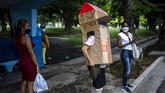 Seorang Nenek di Kuba Tangkal Corona Dengan Kardus Feridia Rojas, a retired nurse, wears a cardboard box as a protective measure against the spread of the new coronavirus, in Havana, Cuba, Wednesday, July 8, 2020. The 82-year-old pensioner shuffles through the streets of Havana on shopping excursions wearing the cardboard box, with a handwritten message that reads in Spanish,