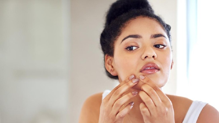 jerawat Shot of a young woman squeezing a pimple on her face in the bathroom
