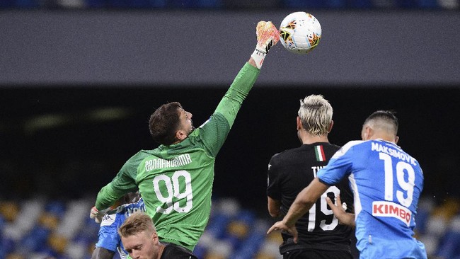 AC Milan goalie Gianluigi Donnarumma (99) reaches out to knock the ball away as Napoli's Nikola Maksimovic, right, tries to head it during a Serie A soccer match at San Paolo Stadium in Naples, Italy, Sunday, July 12, 2020. (Cafaro/LaPresse via AP)