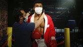 patung Madame Tussauds turki pakai masker In order to raise awareness against the spread of the coronavirus, a worker at Madame Tussauds attraction in Istanbul, places a mask on the wax figure of Muhammad Ali during a photo-op, Saturday, July 11, 2020. Turkish authorities have made the wearing of masks mandatory in most of the country to curb the spread of COVID-19 following an uptick in confirmed cases since the reopening of many businesses. (AP Photo/Emrah Gurel)